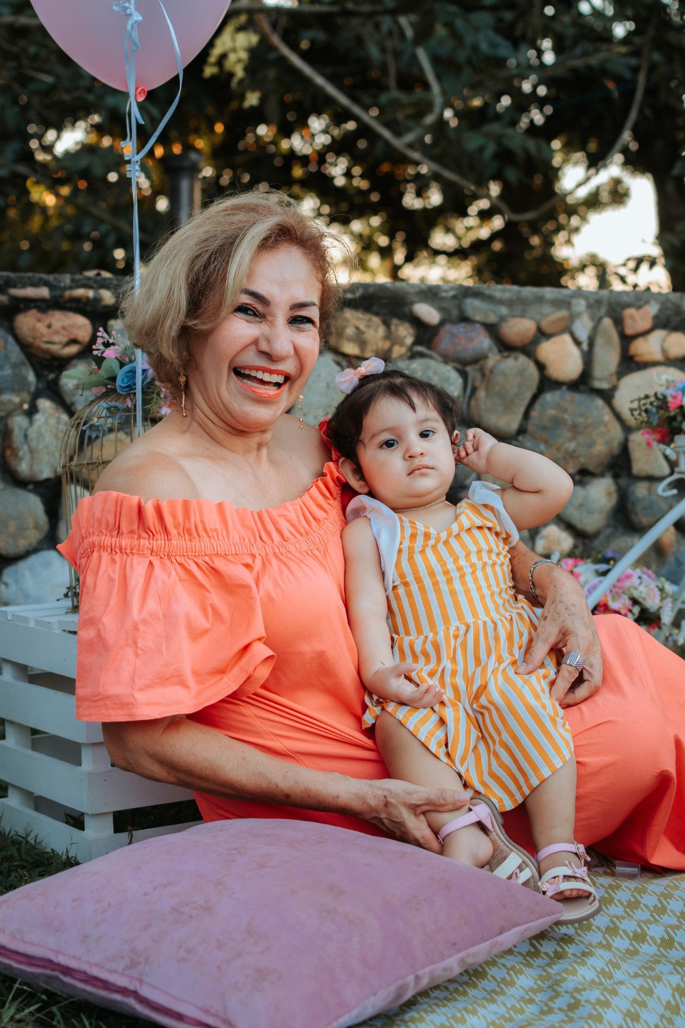 A smiling grandmother holding her baby granddaughter outdoors