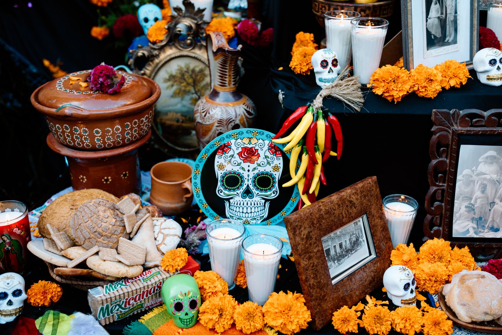 A Día de Muertos ofrenda with marigolds, candles, sugar skulls and framed photos