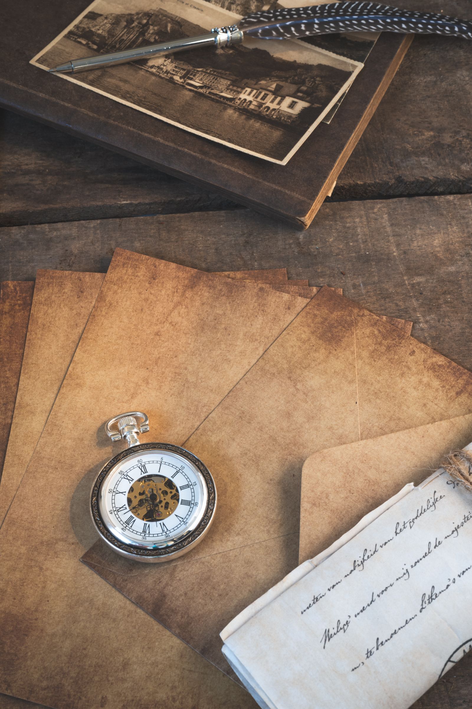 Old letters, a pocket watch and a vintage photograph on a wooden table